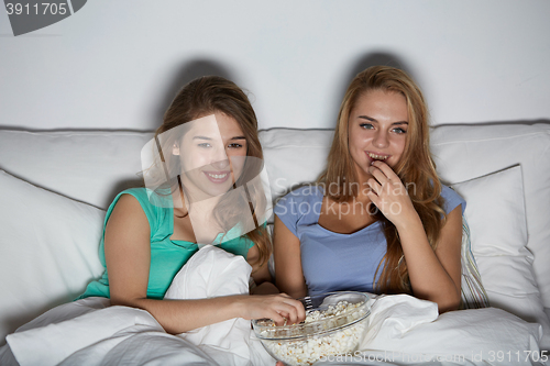 Image of happy friends with popcorn and watching tv at home