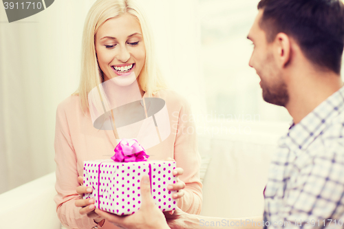 Image of happy man giving woman gift box at home