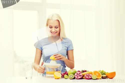 Image of smiling woman squeezing fruit juice at home