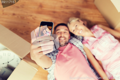 Image of couple taking selfie with smartphone on floor