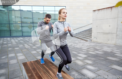 Image of couple making step exercise on city street bench