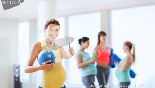 Image of pregnant woman with ball in gym showing thumbs up 