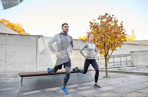 Image of couple doing lunge exercise on city street