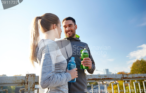 Image of smiling couple with bottles of water outdoors