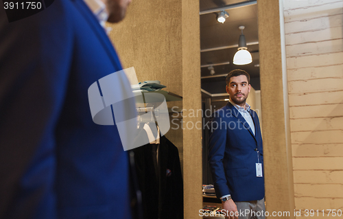 Image of man trying jacket on at mirror in clothing store
