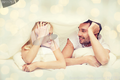 Image of happy couple lying in bed and talking at home