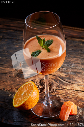 Image of Orange carrot smoothie in glass decorated mint