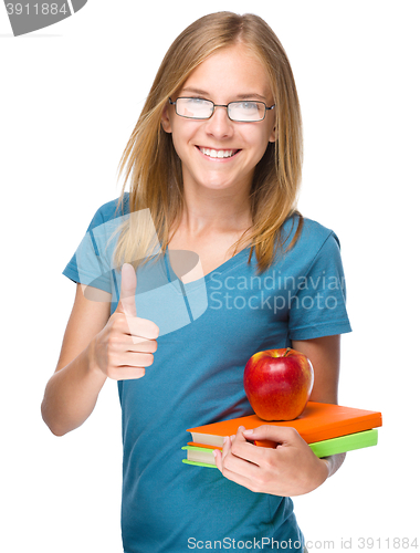 Image of Young student girl is holding book and apple