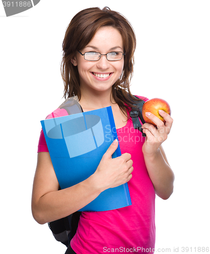 Image of Young student girl is holding book and apple