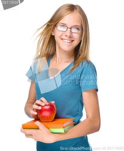 Image of Young student girl is holding book and apple