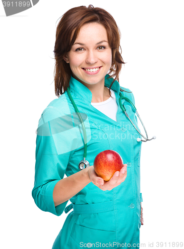 Image of Young lady doctor is holding a red apple