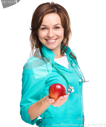 Image of Young lady doctor is holding a red apple