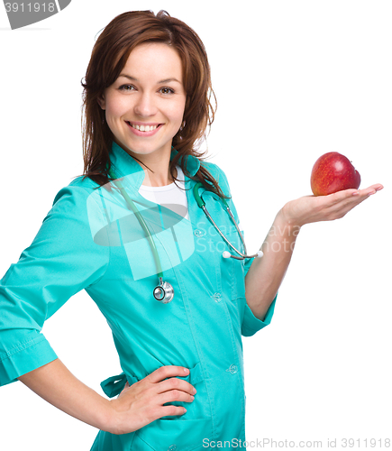 Image of Young lady doctor is holding a red apple