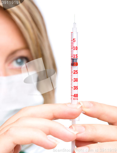 Image of Young nurse is preparing syringe for injection