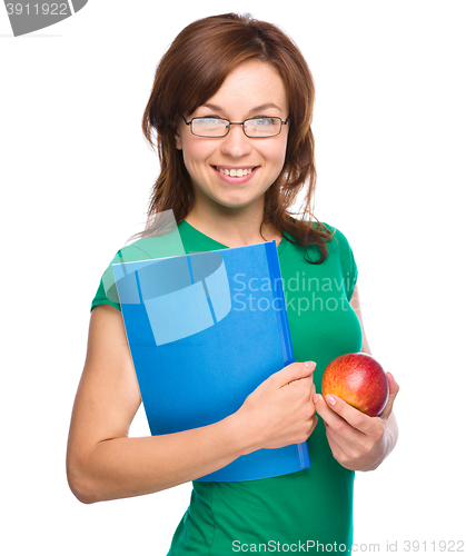Image of Young student girl is holding book and apple