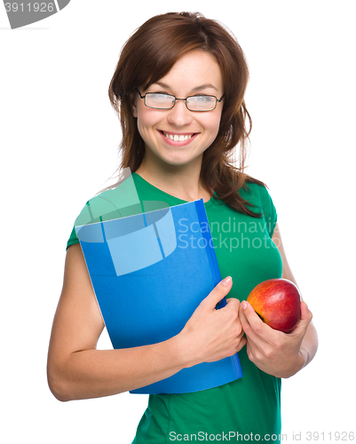 Image of Young student girl is holding book and apple