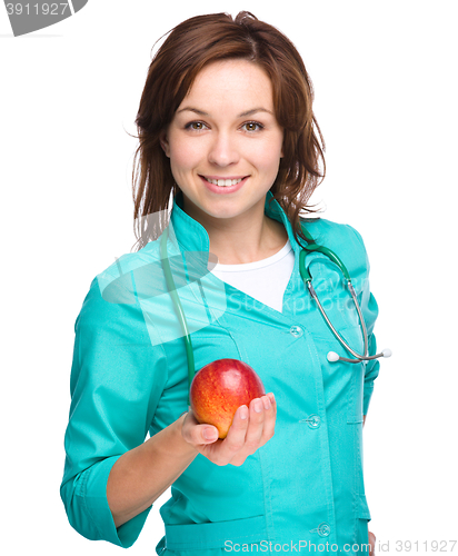 Image of Young lady doctor is holding a red apple