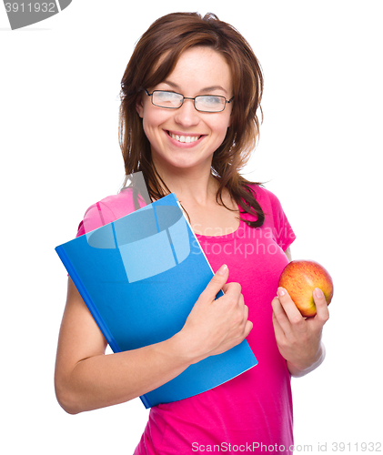 Image of Young student girl is holding book and apple