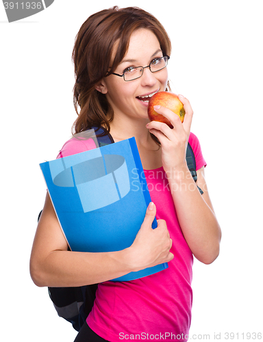 Image of Young student girl is holding book and apple