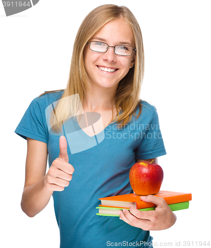 Image of Young student girl is holding book and apple