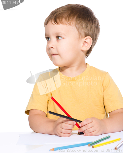 Image of Little boy is drawing using color pencils