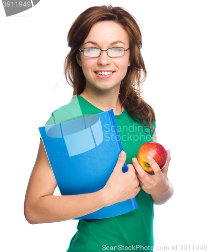 Image of Young student girl is holding book and apple