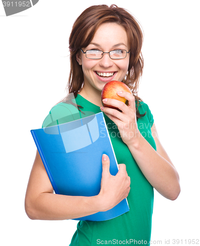 Image of Young student girl is holding book and apple