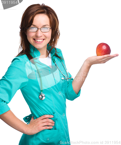 Image of Young lady doctor is holding a red apple