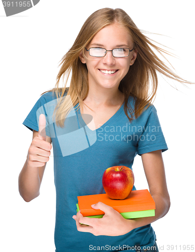 Image of Young student girl is holding book and apple