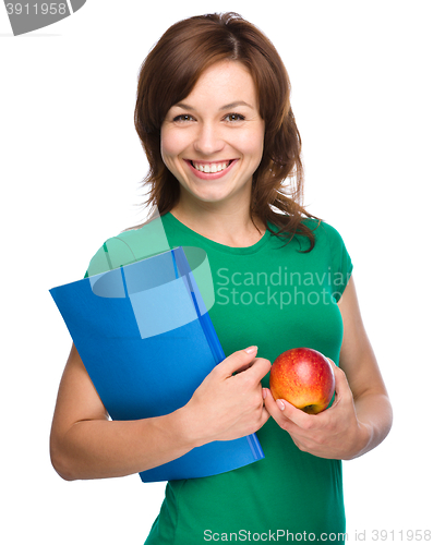 Image of Young student girl is holding book and apple