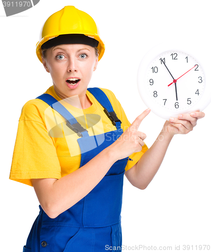 Image of Young construction worker is pointing at clock