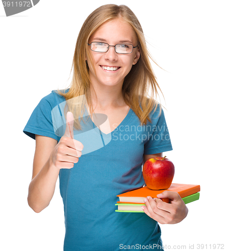 Image of Young student girl is holding book and apple