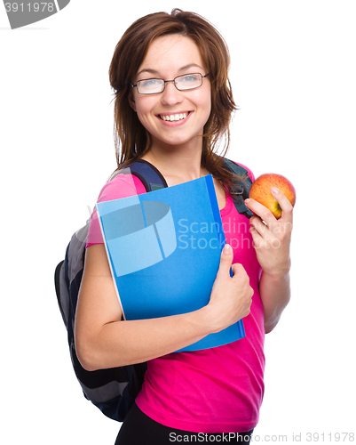 Image of Young student girl is holding book and apple