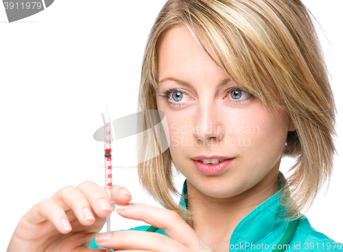 Image of Young nurse is preparing syringe for injection