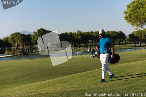 Image of golf player walking and carrying bag