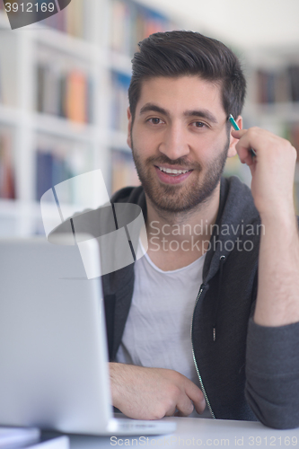 Image of student in school library using laptop for research