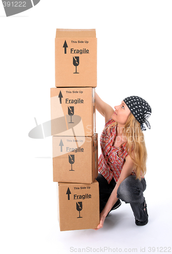 Image of Girl trying to lift a stack of cardboard boxes