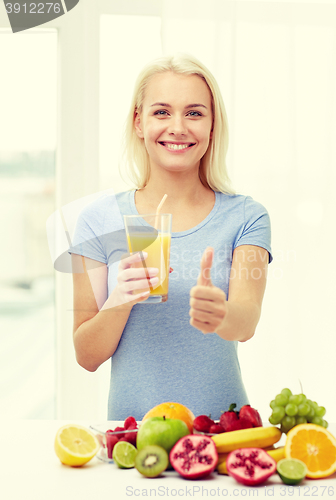 Image of woman drinking fruit juice and showing thumbs up