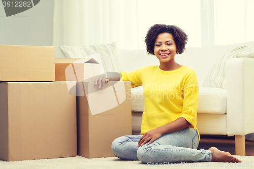 Image of happy african woman with cardboard boxes at home