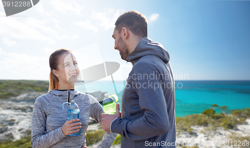 Image of smiling couple with bottles of water outdoors