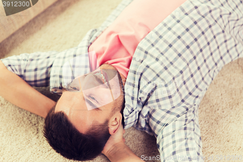 Image of happy man lying carpet or rug at home