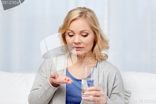 Image of woman with medicine and water glass at home