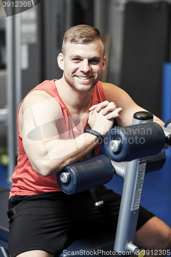 Image of smiling man sitting on exercise bench in gym