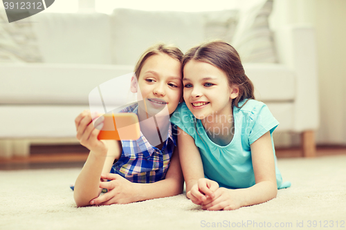 Image of happy girls with smartphone taking selfie at home