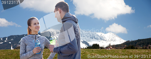 Image of smiling couple with bottles of water outdoors