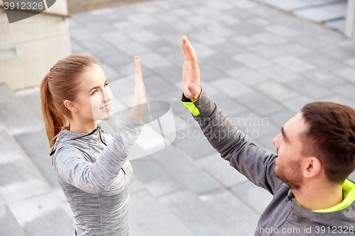 Image of smiling couple making high five on city street