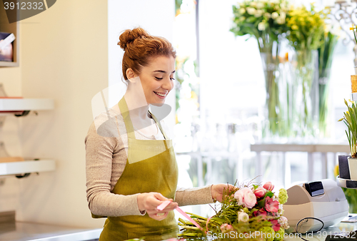 Image of smiling florist woman making bunch at flower shop