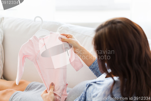 Image of close up of happy woman with baby bodysuit at home