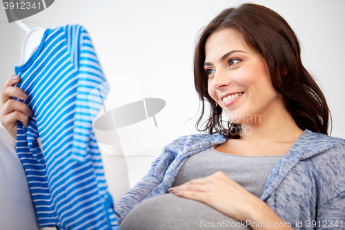 Image of happy woman holding baby boys bodysuit at home