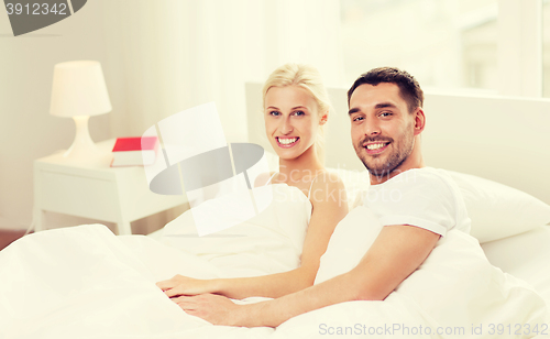 Image of happy couple lying in bed at home